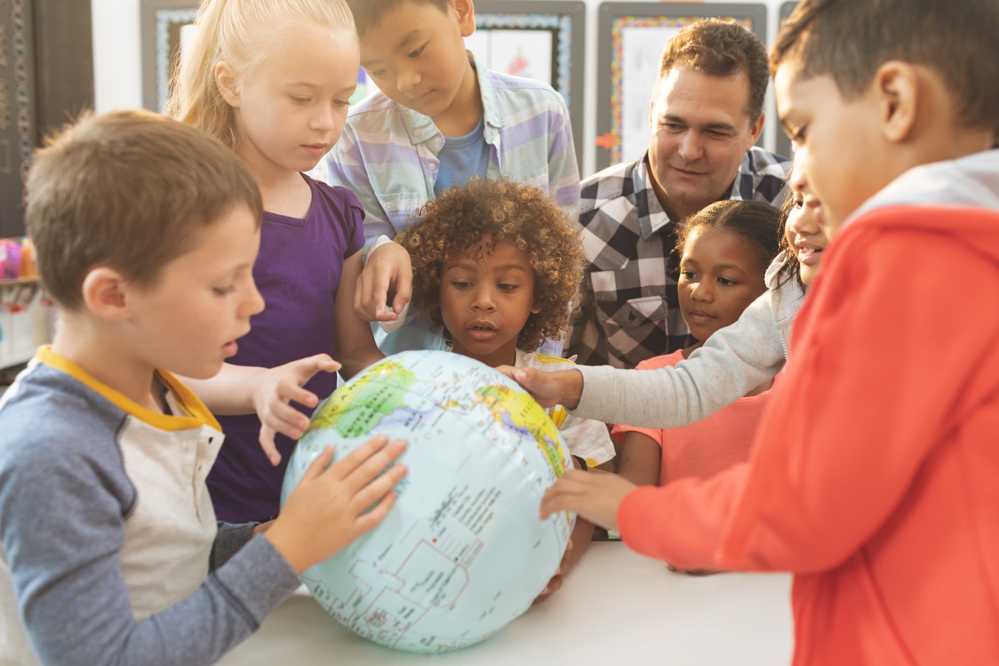Schoolteacher discusing over earth globe in classroom at school