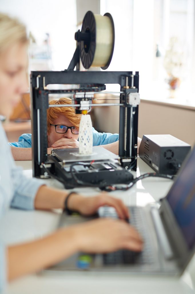 Engineer looking at architectural model in 3d printer in working environment by Pressmaster