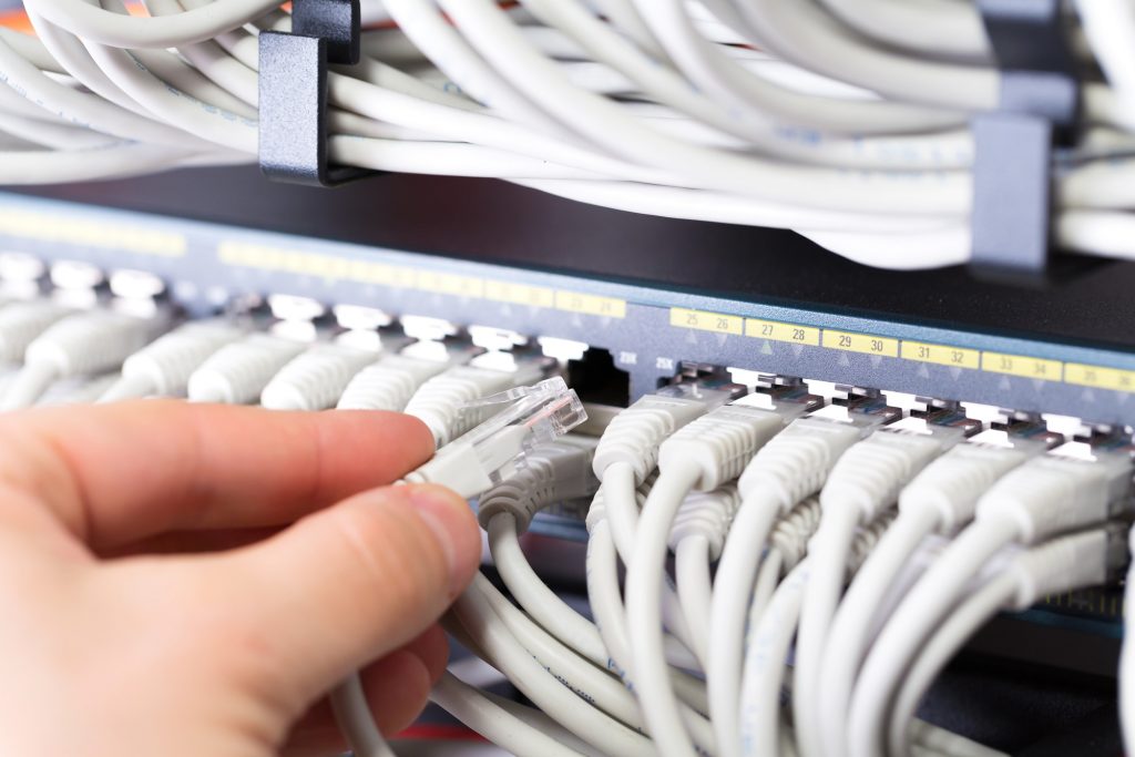 IT consultant connects a network cable into switch in datacenter by kjekol