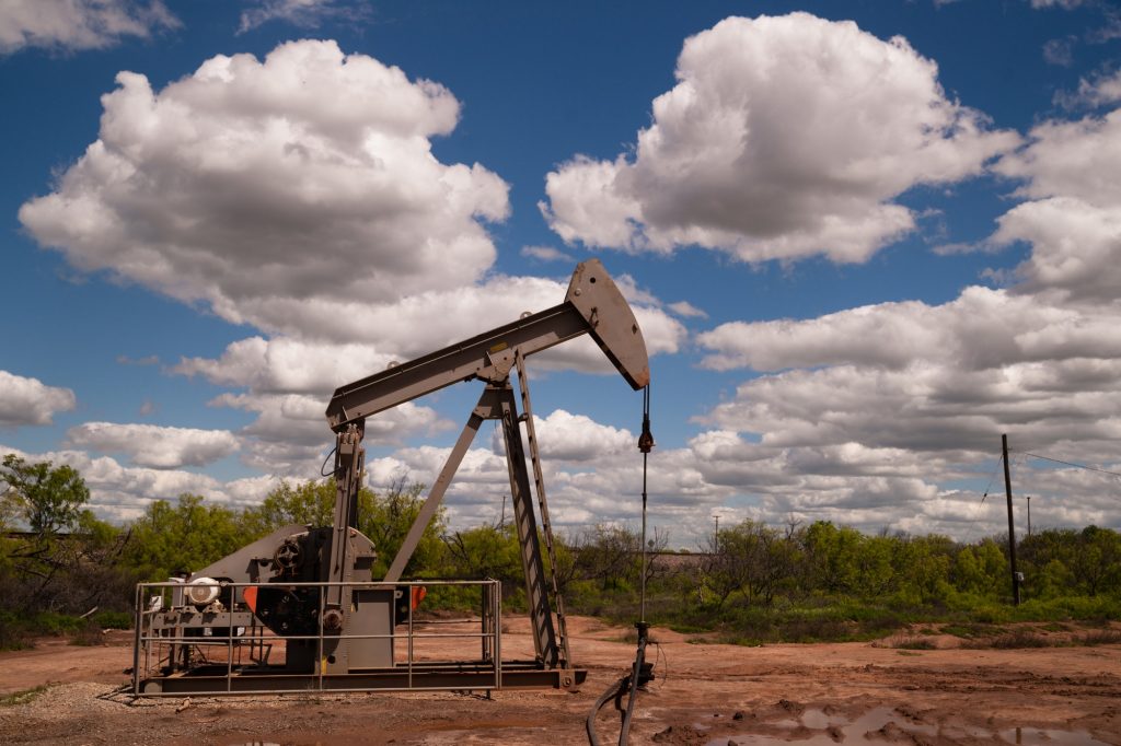 A dramatic sky surrounds this oil pump jack in a muddy bog in the united states by Christopher_Boswell.