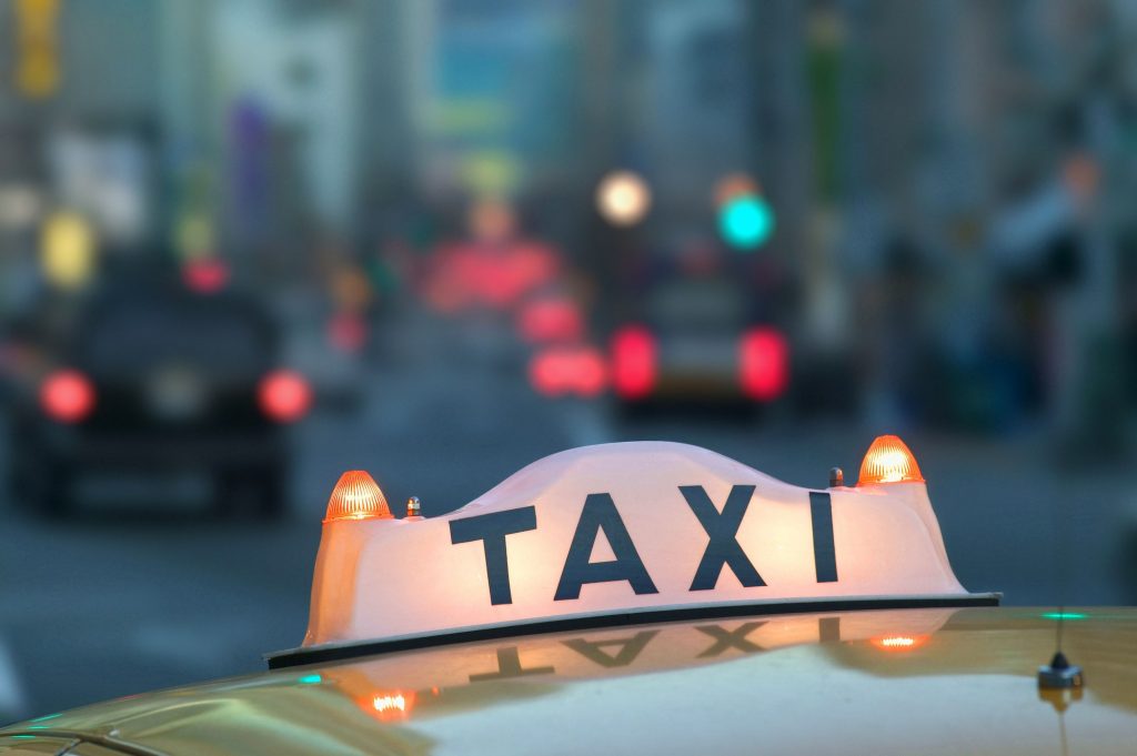 Closeup of a taxi sign on top of a taxi cab in the city at night.